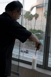 Fr. David Gallardo, pastor of the Cathedral of Our Lady of the Angels, lights a candle in support of medical workers and their families along the edge of the Cathedral of Our Lady of the Angels plaza overlooking the 101 freeway in downtown Los Angeles. (Sarah Yaklic)