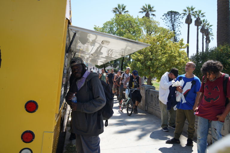 Una larga fila de personas espera para recibir comida caliente del camión de alimentos Feed My Poor. «Estamos cumpliendo la misión de Dios», dice Marisol Ortiz, una de las trabajadoras del camión. (John Rueda)