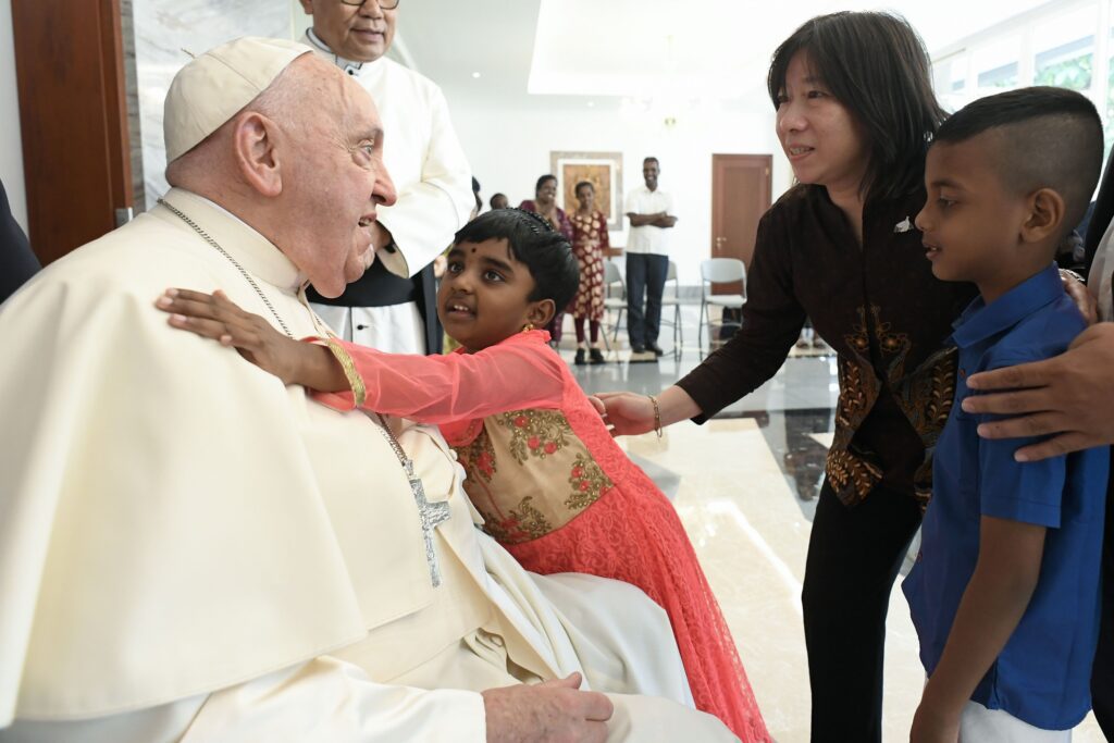 El Papa Francisco recibe el abrazo de una niña mientras se reúne con migrantes, refugiados, huérfanos, ancianos y enfermos en la nunciatura apostólica en Yakarta, Indonesia, el 3 de septiembre de 2024. Las personas con las que se reunió el Papa son asistidas por la Comunidad de Sant'Egidio, las hermanas dominicas y el Servicio Jesuita a Refugiados. (Foto CNS/Vatican Media)