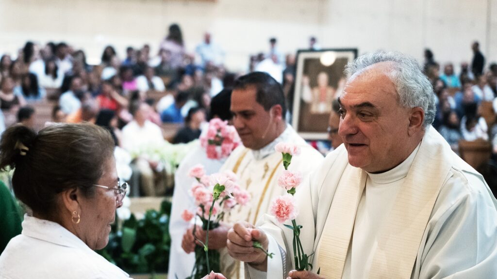 Mons. Antonio Cacciapuoti, a la izquierda, y el padre Peter Saucedo entregan rosas a las madres durante una Misa del Día de las Madres en la Catedral de Nuestra Señora de los Ángeles, el 11 de mayo. Cacciapuoti es el rector de la catedral, mientras que Saucedo reside allí. (Victor Alemán)