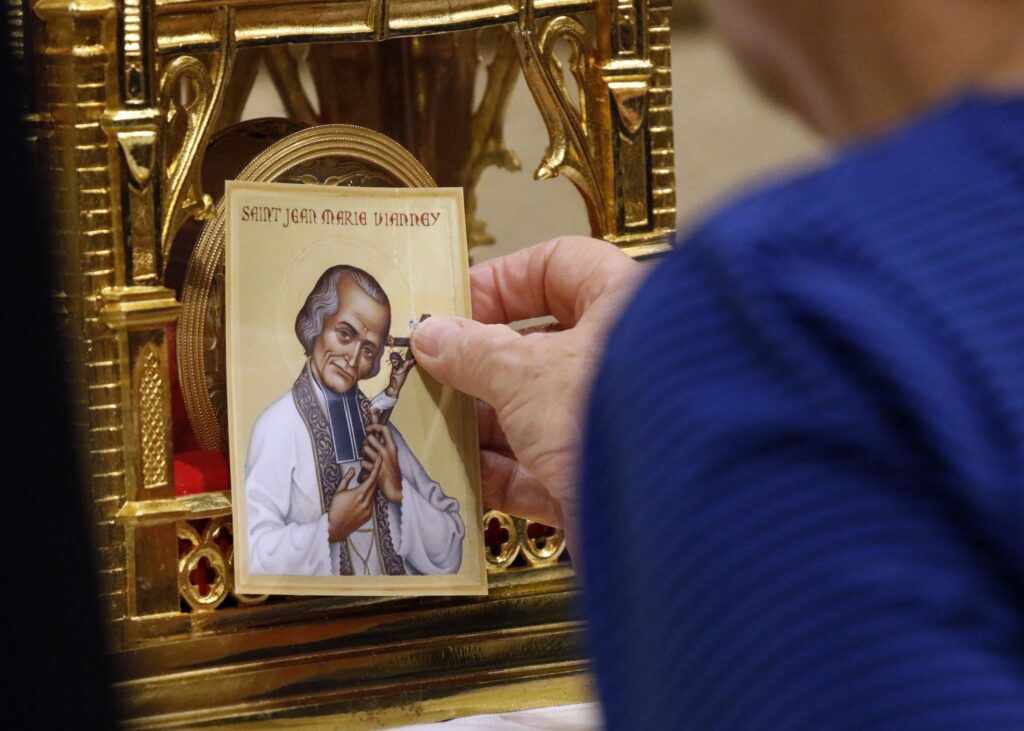 Una mujer que sostiene una tarjeta de oración toca un relicario que contiene el corazón incorrupto de San Juan Vianney en la Catedral de San Patricio en la ciudad de Nueva York el 7 de abril de 2019. La reliquia del sacerdote francés del siglo XIX y patrono de los párrocos está en una gira de seis meses por Estados Unidos patrocinada por los Caballeros de Colón (CNS photo/Gregory A. Shemitz)