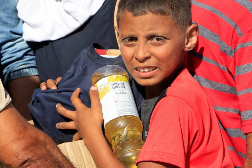 A young person carries food aid as Palestinians seeking aid gather near a distribution site in Rafah, in the southern Gaza Strip, May 27, 2025, after being displaced by the Israeli military offensive. The distribution is run by the U.S.-backed Gaza Humanitarian Foundation. (OSV News photo/Hatem Khaled, Reuters)