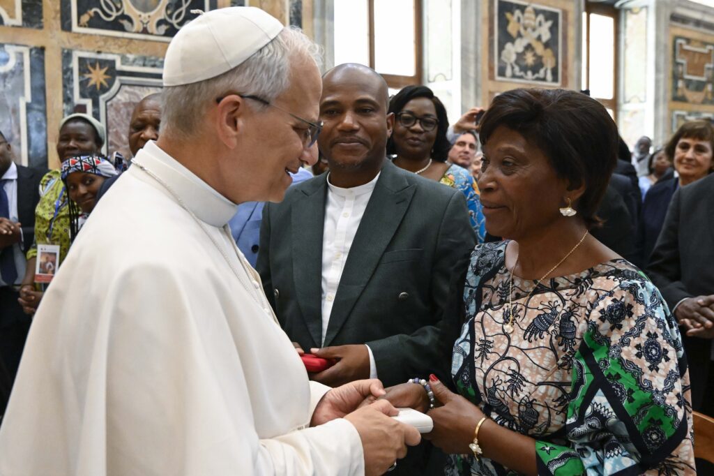 El Papa León XIV saluda a Gertrude Kamara Ntawiha, madre del recién beatificado mártir congoleño Beato Floribert Bwana Chui, durante una audiencia en la Sala Clementina del Vaticano el 16 de junio de 2025. El hermano del Beato Bwana Chui, Tresor, observa. (CNS photo/Vatican Media)
