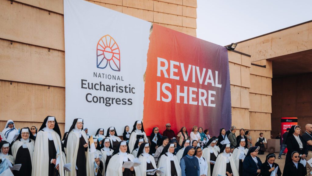 Asistentes a la Misa de Corpus Christi en la Catedral de Nuestra Señora de los Ángeles, el 22 de junio, en la plaza exterior bajo una pancarta del Avivamiento Eucarístico Nacional. (Isabel Cacho)