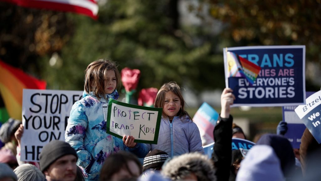 Personas sostienen carteles mientras la Corte Suprema de EE.UU. escucha los argumentos sobre una apelación de la administración del entonces presidente Joe Biden, respecto a la decisión de un tribunal inferior que respaldó una prohibición en Tennessee —impulsada por los republicanos— sobre la atención médica de afirmación de género para menores transgénero, en Washington D.C., el 4 de diciembre de 2024. El máximo tribunal del país confirmó la ley estatal de Tennessee el 18 de junio. (OSV News/Benoit Tessier, Reuters)