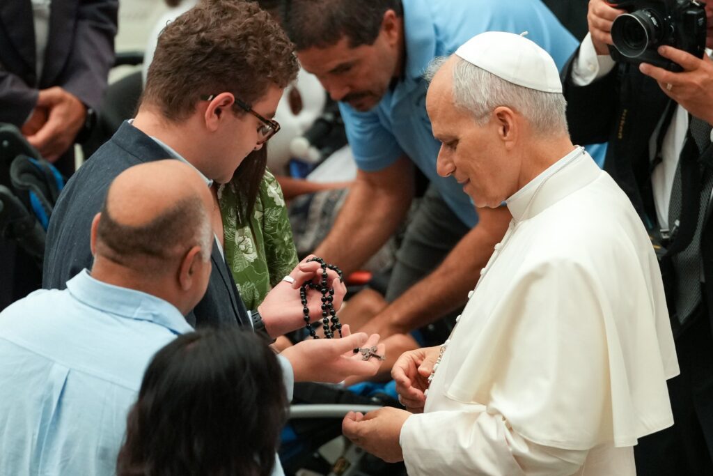El papa León XIV saluda a un joven que sostiene un rosario durante su audiencia general en la sala Pablo VI del Vaticano, el 13 de agosto de 2025. (Foto CNS/Vatican Media)