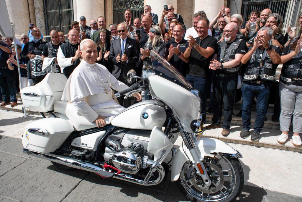 El papa León XIV posa sobre una motocicleta BMW R18 modificada que le han regalado los miembros del club de motociclistas alemán Jesus Bikers y representantes de Missio Austria, las sociedades misioneras pontificias en Austria, en la plaza de San Pedro del Vaticano, el 3 de septiembre de 2025. La moto será subastada por Sotheby's y Missio Austria utilizará el dinero para ayudar a construir una escuela para los niños que trabajan en las minas de mica en Madagascar. (Foto CNS/Vatican Media)
