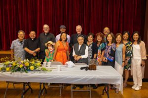 Erin Yoshi, al centro, vestida de naranja, artista principal del mural, posa con sacerdotes, otros artistas y simpatizantes durante la celebración. (Kokawa Photography)