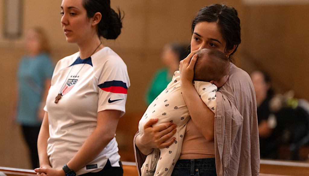 Una madre sostiene a su bebé durante la Misa en Reconocimiento a Todos los Inmigrantes en la Catedral de Nuestra Señora de los Ángeles, el 21 de septiembre. (Evan Lirette)