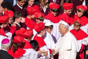 El Papa León XIV posa para una foto con alumnos de la Academia Nuestra Señora del Monte Carmelo (Our Lady of Mount Carmel Academy) de Chicago, entre los que se encuentran Augie Wilk, alumno de cuarto curso, vestido de papa, y el cardenal Blase J. Cupich, de Chicago, al término de la audiencia general en la plaza de San Pedro del Vaticano, el 8 de octubre de 2025. Los alumnos acapararon la atención mundial cuando celebraron un cónclave simulado en su colegio el 6 de mayo, en el que eligieron a su propio “papa”, Wilk, que tomó el nombre de “Papa Agustín”, pocos días antes de la elección del Papa León, quien también de Chicago y agustino. (Foto CNS/Lola Gómez)