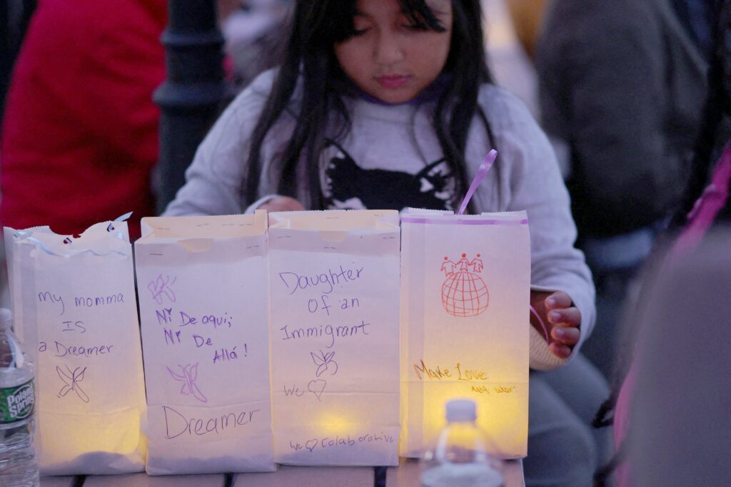 Zuanny, una niña de ocho años, coloca luminarias con mensajes sobre su madre, una “dreamer” del DACA, sobre ella misma y sobre sus hermanas durante una vigilia en La Colaborativa, en Chelsea, Massachusetts, el 10 de octubre de 2025, en apoyo a la comunidad afectada por las redadas y detenciones del la Oficina de Inmigración y Control de Aduanas (ICE). (Foto OSV News/Brian Snyder, Reuters)