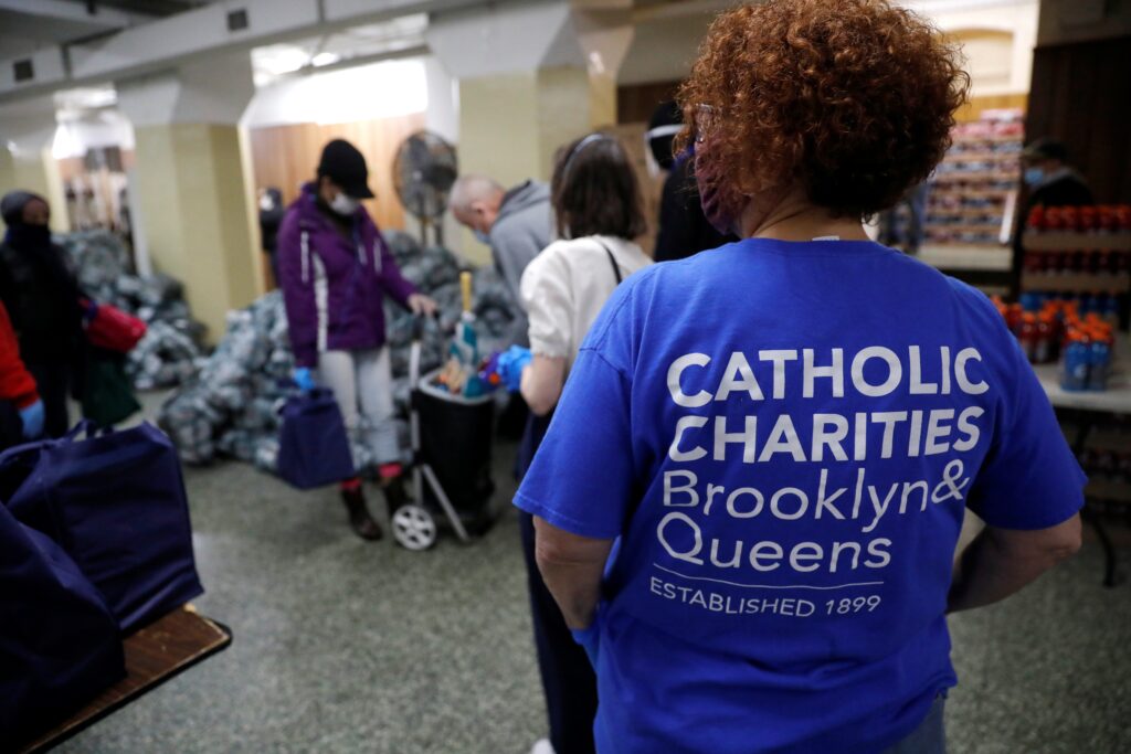 NEW YORK CATHOLIC CHARITIES PANDEMIC | Angelus en Español Un voluntario en la ciudad de Nueva York observa cómo las personas reciben comida gratis en un banco de alimentos para residentes necesitados gestionado por Catholic Charities Brooklyn and Queens el 24 de abril de 2020. (Foto de OSV News/Mike Segar, Reuters)