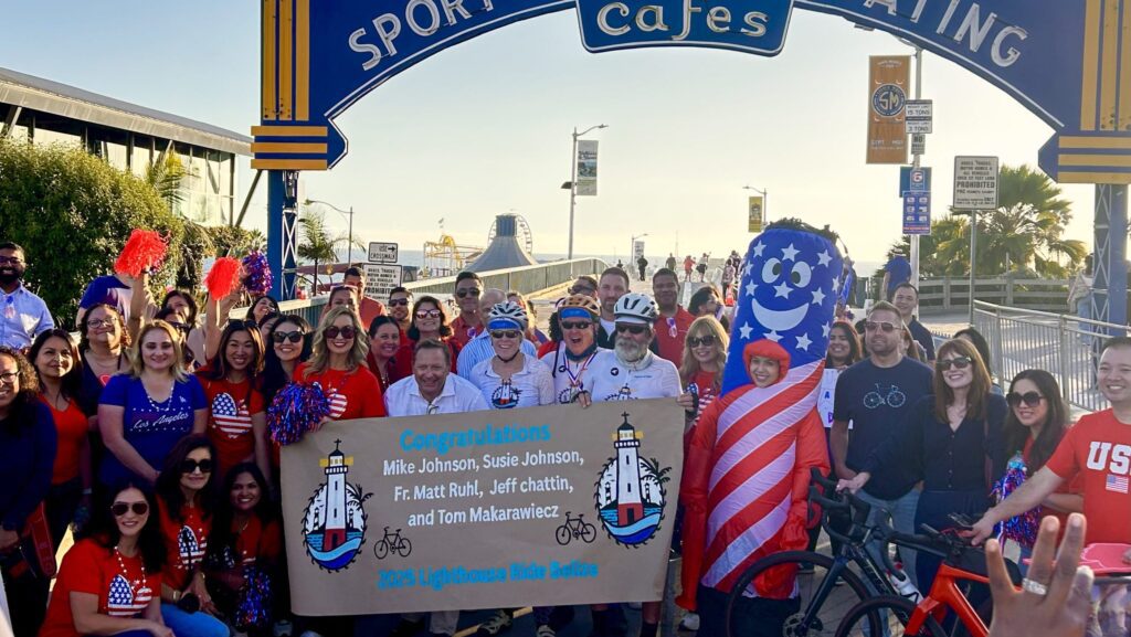 El padre Matt Ruhl, SJ (al centro, con barba), posa con otros ciclistas y simpatizantes tras completar The Lighthouse Ride el 1 de octubre en Santa Mónica, luego de partir desde Maine el 15 de julio. (Tom Hoffarth)