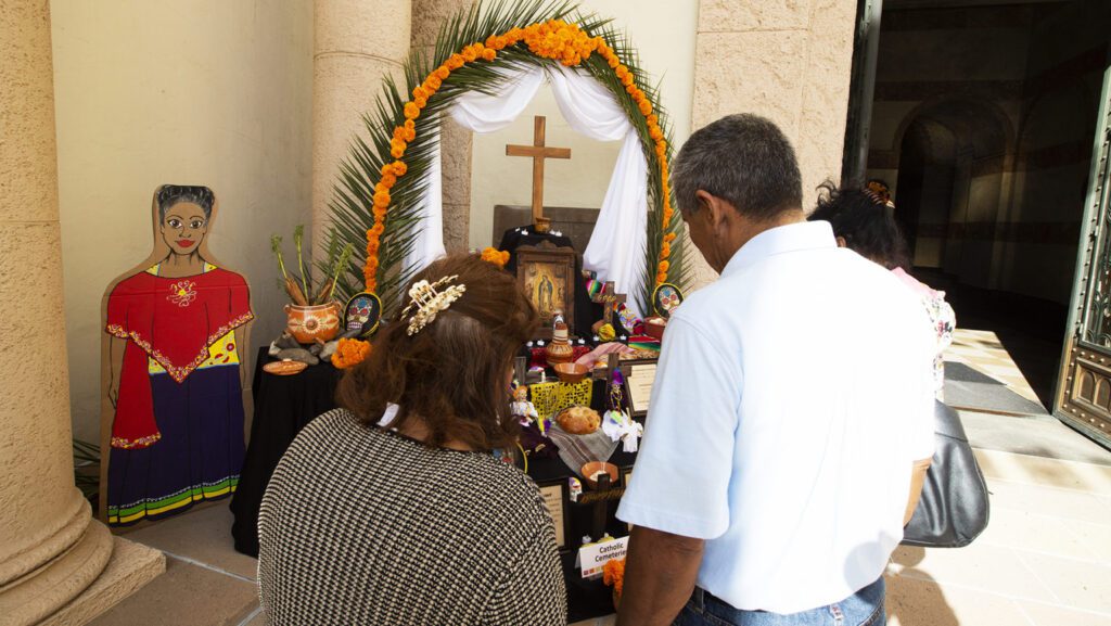 DAY_OF_THE_DEAD_16_VL5A8584-e1760884182313-1536x865 1 | Angelus en Español Una pareja ora frente a un altar dedicado al Día de los Muertos en el Cementerio Calvary de East Los Ángeles, en una foto sin fecha. (Víctor Alemán)