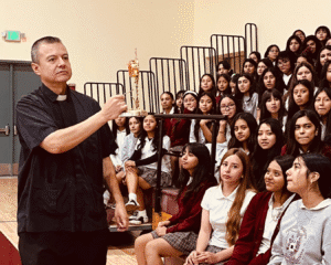 Carlo_Acutis_Bishop_Conaty2 | Angelus en Español El padre Mario Torres, párroco de St. Thomas the Apostle, muestra la reliquia de San Carlo Acutis a alumnas de la secundaria Bishop Conaty-Our Lady of Loretto el 21 de octubre. (Foto cortesía)