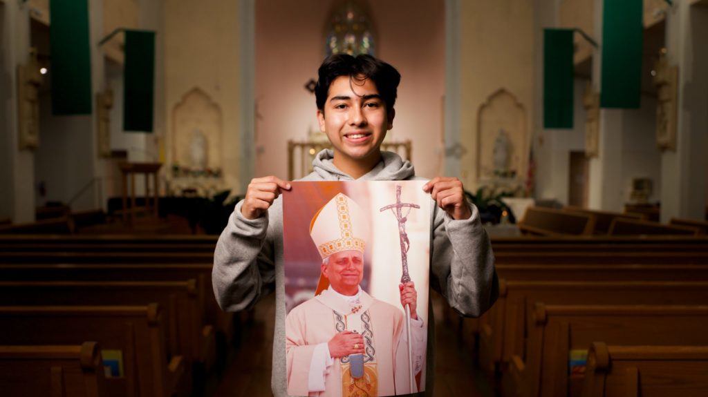 Ezequiel Ponce, de 17 años, con un retrato del Papa León XIV dentro de la iglesia Our Lady of Perpetual Help en Downey. (Reese Cuevas)