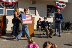 Una bandera estadounidense hecha a mano por los estudiantes de Holy Angels es presentada a Joe “Peppy” Sciarra, un veterano de la Segunda Guerra Mundial de 101 años, durante un evento por el Día de los Veteranos en la escuela de Arcadia el 10 de noviembre. (Lawrence Lane)