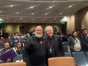 El obispo Matt Elshoff y el padre Brendan Busse, SJ, dentro de la audiencia congresional del 24 de noviembre sobre las redadas migratorias federales, en el edificio del Distrito Metropolitano de Agua de LA. (Isaac Cuevas)
