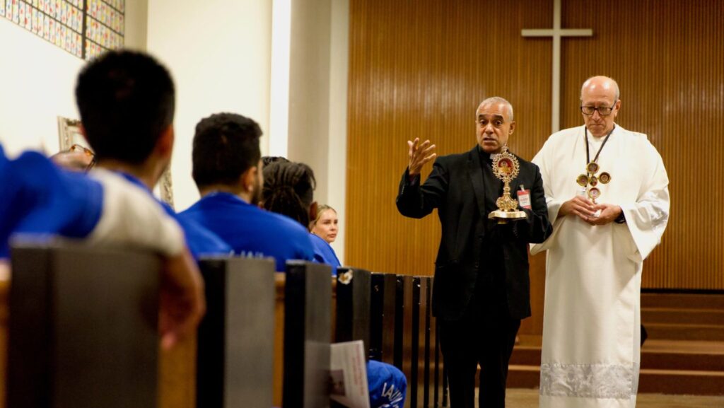 Mons. Anthony Figueiredo, sacerdote en Asís, Italia, habla con los reclusos de la cárcel central de hombres de Los Ángeles sobre la vida de San Carlo Acutis antes de la Misa del 20 de octubre. A la derecha, el diácono Fermín López. (Reese Cuevas)