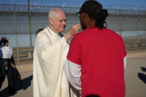 DSC02791-copy-1536x1024 | Angelus en Español El obispo auxiliar de Los Ángeles, Matt Elshoff, distribuye la Comunión a un detenido durante la inusual Misa celebrada en el centro del ICE en Adelanto. (Conferencia Católica de California)