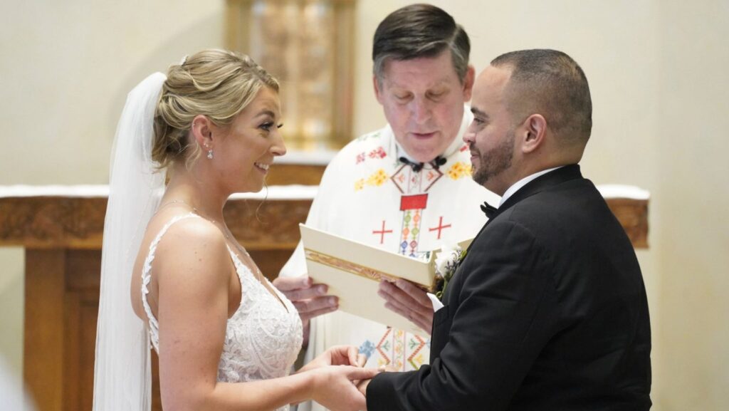 Christina MacDougall coloca un anillo de bodas en el dedo de Julio Prendergas mientras Mons. Francis J. Schneider oficia la Misa de su boda el 20 de agosto de 2021 en la iglesia St. John the Baptist, en Wading River, Nueva York. (CNS/Gregory A. Shemitz)