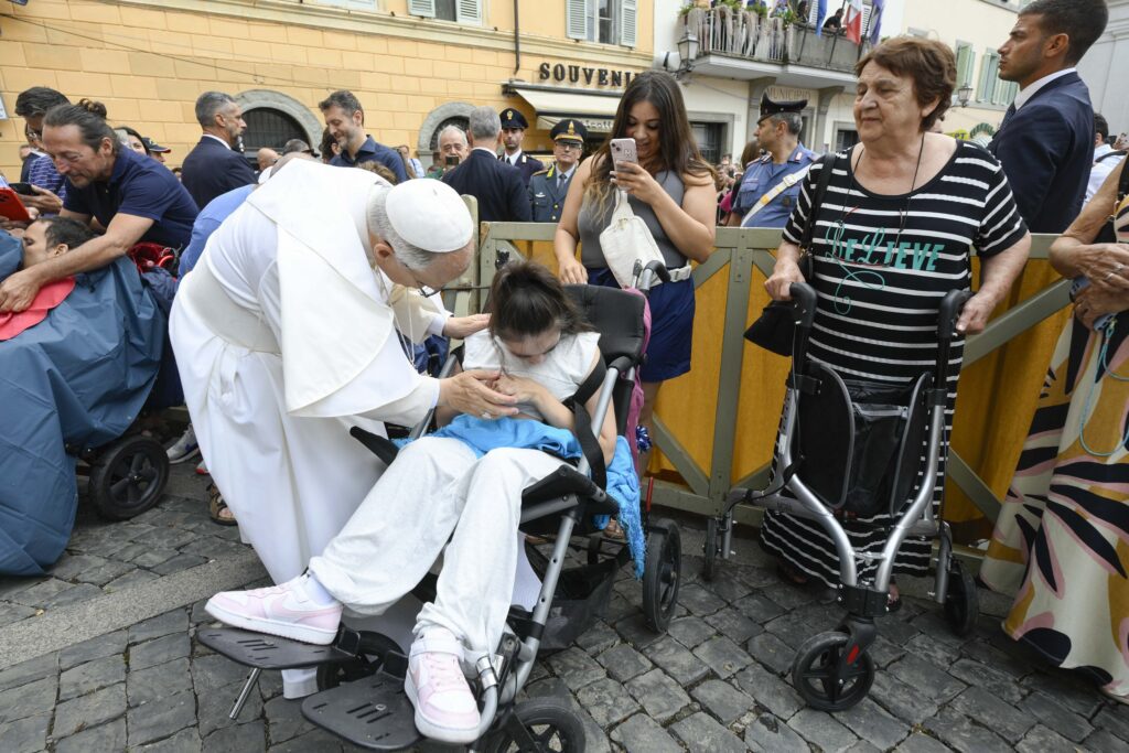 El papa León XIV saluda a una joven en silla de ruedas tras dirigir el rezo del Ángelus frente al palacio papal de Castel Gandolfo, Italia, el 17 de agosto de 2025. (Foto CNS/Vatican Media)