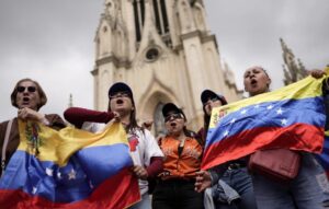 Personas sostienen banderas mientras venezolanos que viven en Colombia se manifiestan frente a la Basílica Menor de Nuestra Señora de Lourdes en Bogotá el 4 de enero, por una transición democrática en Venezuela, tras los ataques de Estados Unidos que capturaron al presidente venezolano Nicolás Maduro y a su esposa, Cilia Flores. (OSV News/Sergio Acero, Reuters)