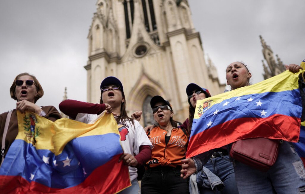 Varias personas ondean banderas venezolanas mientras participan de una manifestación frente a la Basílica Menor de Nuestra Señora de Lourdes en Bogotá el 4 de enero de 2026, pidiendo una transición democrática, tras los ataques lanzados por Estados Unidos contra Venezuela, que resultaron en la captura del presidente Nicolás Maduro y su esposa, Cilia Flores. (Foto OSV News/Sergio Acero, Reuters)