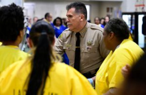 El sheriff del condado de Los Ángeles, Robert Luna, intercambió abrazos y apretones de manos con internas durante el saludo de la paz en la Misa de Navidad. (John McCoy)