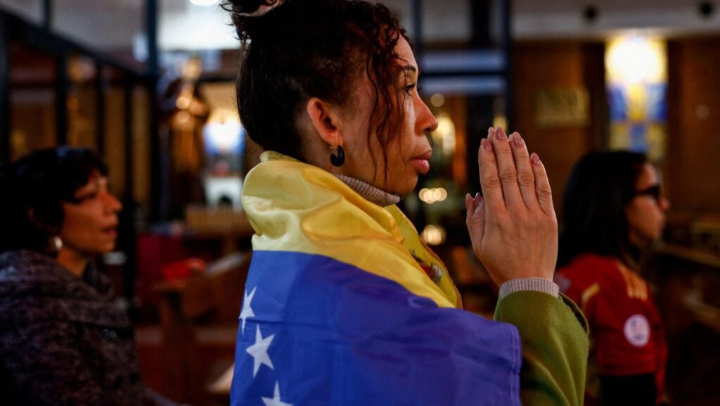 Una mujer envuelta en una bandera venezolana reza en la Iglesia del Santísimo Redentor en Roma el 4 de enero de 2026, tras un ataque estadounidense contra Venezuela, donde el presidente Nicolás Maduro y su esposa, Cilia Flores, fueron capturados el día anterior. (Foto de OSV News/Matteo Minnella, Reuters)