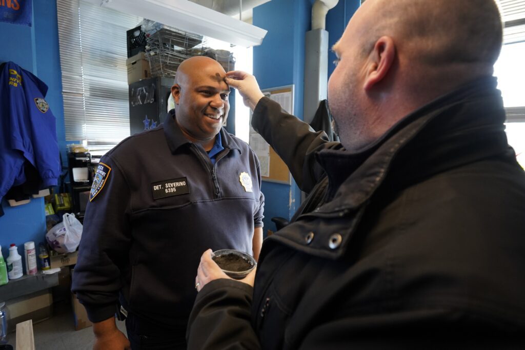 El padre Sean Suckiel, párroco de la iglesia Holy Family en Fresh Meadows, Nueva York, impone las cenizas al detective José Severino, del Departamento de Policía de Nueva York, en la comisaría 107 de Fresh Meadows, el 14 de febrero de 2024. El padre Suckiel visitó la comisaría y dos parques de bomberos de la zona para distribuir cenizas a los servicios de emergencia y al resto del personal el Miércoles de Ceniza. (Foto de OSV News/Gregory A. Shemitz)