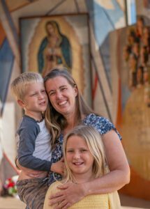 Sarah Ray y su hijo Tyler, de 3 años, y su hija Anna, de 8, posan antes de la Misa anual del Día Mundial del Enfermo en la Catedral de Nuestra Señora de los Ángeles el 7 de febrero. La familia Ray perdió su hogar durante el incendio Eaton en 2025, tras la muerte del esposo y padre Casey Ray en 2022. (Juanito Holandez Jr.)