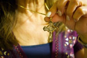 Bernadette, una católica con familia en Jordania, muestra el collar con cruz que compró en ese país hace 30 años durante la Misa en la iglesia St. Joseph en Pomona el 7 de marzo. (Kimmy Chacón)