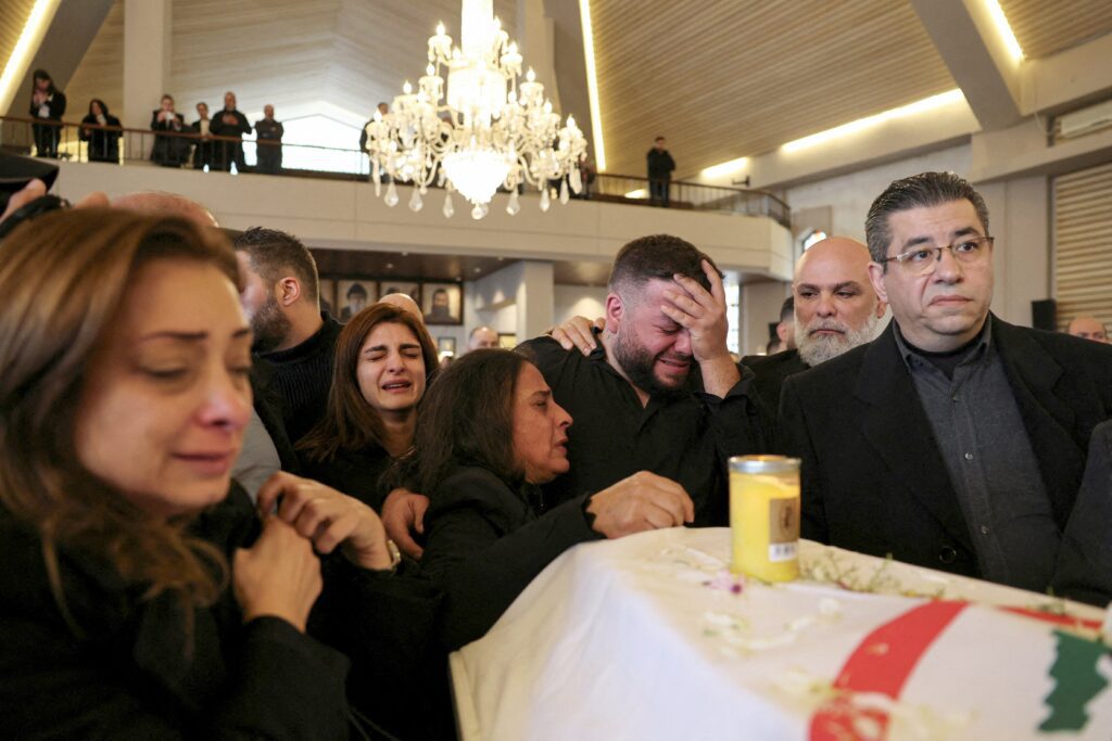Dolientes se congregan alrededor de un ataúd cubierto con una bandera durante el funeral de Pierre Moawad, un funcionario del partido cristiano Fuerzas Libanesas, y de su esposa, Flavia, en la iglesia de San Simón en Yahchouch, Líbano, el 7 de abril de 2026. La pareja falleció a consecuencia de un ataque israelí contra un apartamento al este de Beirut, ocurrido a última hora del 5 de abril. (Foto OSV News/Yara Nardi, Reuters)