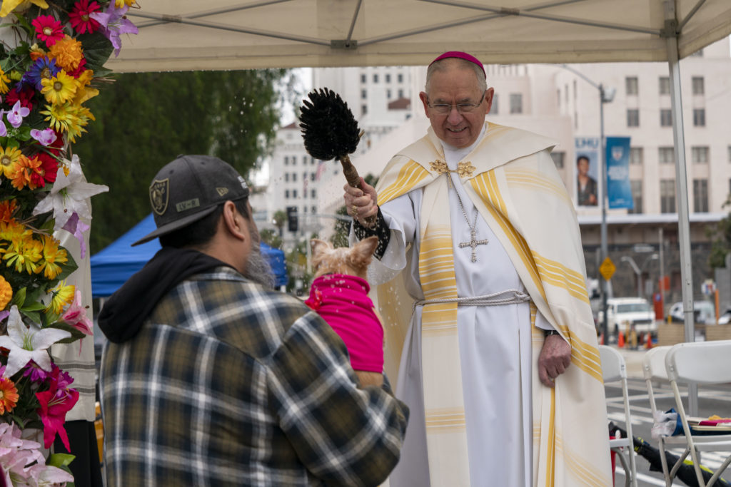 El arzobispo José H. Gomez rocía agua bendita sobre un perro durante el evento de Bendición de los Animales en 2024. (Arquidiócesis de Los Ángeles)