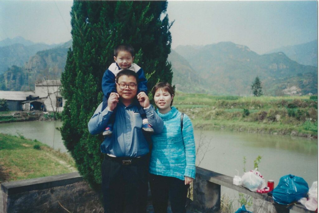 Shengda (Martin) Zhu posa junto a sus padres durante una visita a las tumbas de sus abuelos en China. (Foto enviada)