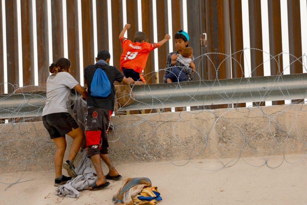 Migrantes que buscan asilo en Estados Unidos intentan cruzar una valla de alambre de púas instalada para impedir el ingreso al país, vistos desde Ciudad Juárez, México, el 4 de junio de 2024. (Foto OSV News/Jose Luis Gonzalez, Reuters).