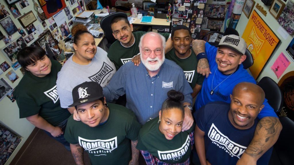 El sacerdote jesuita Greg Boyle, fundador de Homeboy Industries en Los Ángeles, posa para una fotografía junto a participantes del programa en esta imagen sin fecha. El reconocido programa de intervención en pandillas lanzó una campaña de recaudación de fondos de 100 millones de dólares para ampliar su labor, iniciada con una donación de 10 millones de dólares de Frank McCourt Jr., multimillonario egresado de la Universidad de Georgetown y fundador de la Escuela McCourt de Políticas Públicas. La campaña fue promovida durante una cumbre celebrada el 12 de junio de 2026 en la Escuela McCourt. (Foto OSV News/cortesía de Homeboy Industries)