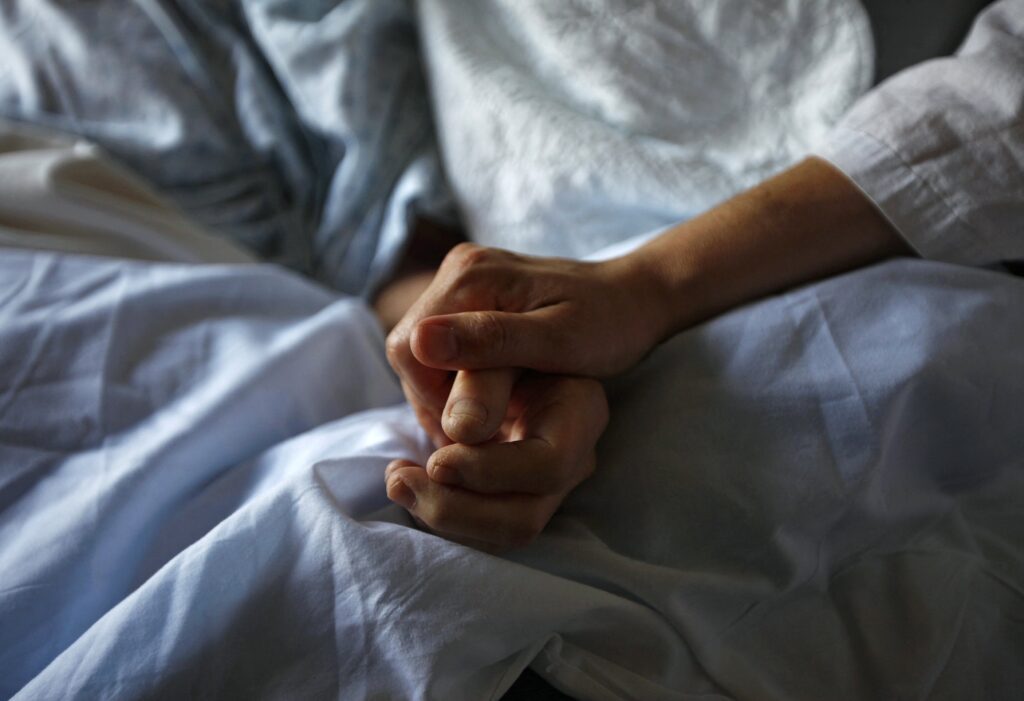 Una mujer sostiene la mano de su madre, que está muriendo de cáncer, durante sus últimas horas en un hospital de cuidados paliativos en Winnipeg, Canadá, el 24 de julio de 2010. (Foto OSV News/Shaun Best, Reuters)