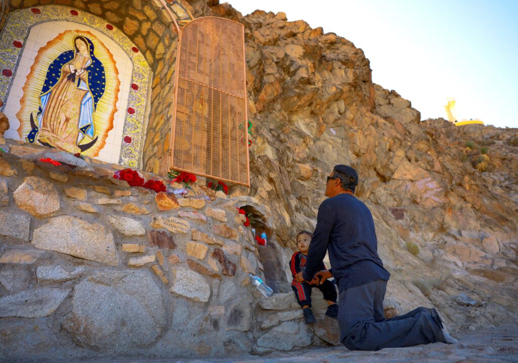 Un hombre reza con un niño ante una imagen de Nuestra Señora en el Monte Cristo Rey, en Sunland Park, Nuevo México, durante una peregrinación celebrada el 23 de noviembre de 2024 con motivo de la festividad de Cristo Rey. La Diócesis de Las Cruces, Nuevo México, calificó los planes de la Administración Trump de expropiar terrenos del lugar de peregrinación para construir un tramo del muro fronterizo entre Estados Unidos y México como una "afrenta a la libertad religiosa" en un escrito de oposición presentado el 19 de junio ante la Corte Federal de Distrito de Nuevo México. (Foto OSV News/José Luis González, Reuters)