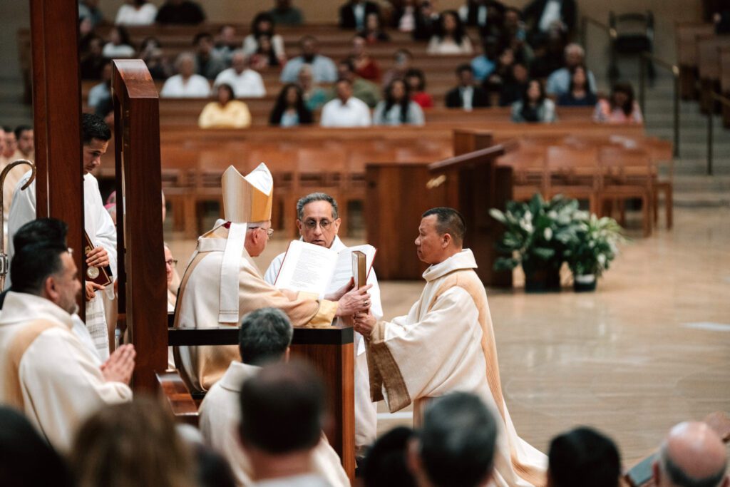 El recién ordenado diácono permanente Anton Trang Dang recibe el Libro de los Evangelios de manos del Arzobispo José H. Gomez durante la misa de ordenación celebrada el 6 de junio en la Catedral de Nuestra Señora de los Ángeles. (Peter Lobato)