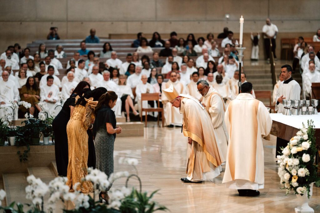 El Arzobispo José H. Gomez hace una reverencia a algunas de las esposas de los nuevos diáconos después de que llevaran las ofrendas al altar durante la misa de ordenación celebrada el 6 de junio en la Catedral de Nuestra Señora de los Ángeles. (Peter Lobato)