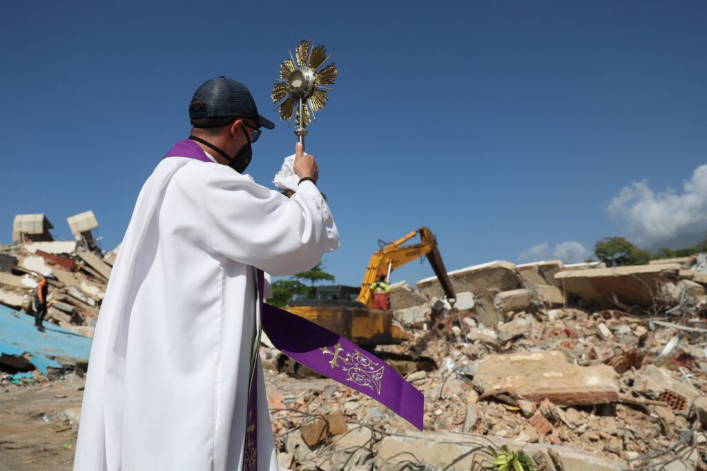 Un sacerdote sostiene una custodia frente a un edificio colapsado en La Guaira, Venezuela, el 1 de julio de 2026, tras los terremotos. Dos devastadores sismos sacudieron el país el 24 de junio con apenas segundos de diferencia y dejaron al menos 3.500 muertos, una cifra que, según los expertos, podría ser mucho mayor. (Foto OSV News/Ricardo Arduengo, Reuters)