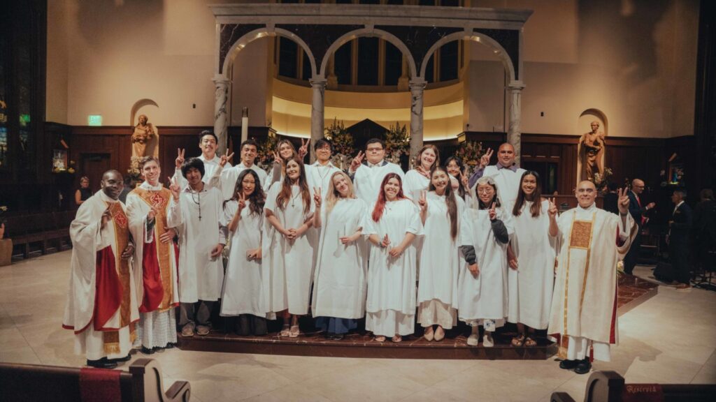 Los nuevos católicos hacen la tradicional seña de "Fight On" de la Universidad del Sur de California (USC) al finalizar la misa de la Vigilia Pascual. (Centro Católico Caruso de la USC)