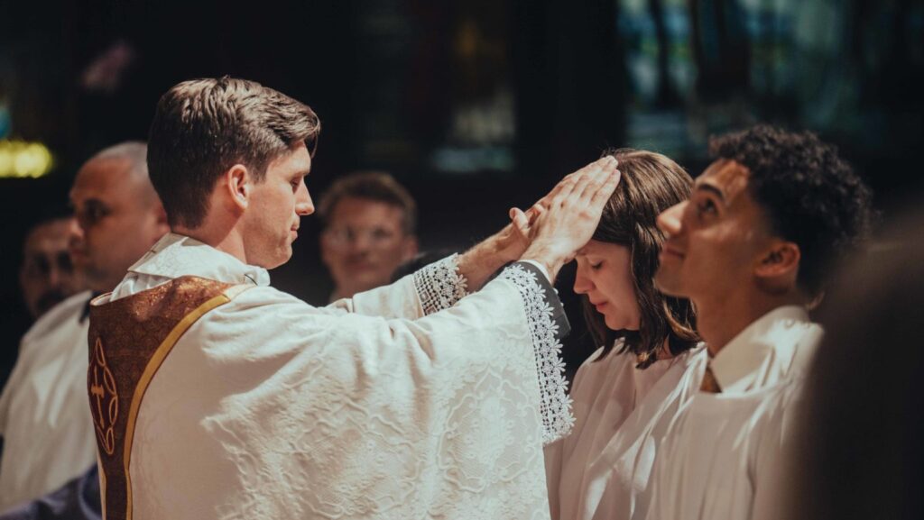 El padre Matthew Wheeler, párroco de Our Savior en la USC, bendice a quienes se incorporan a la Iglesia católica durante la misa de la Vigilia Pascual del 4 de abril. (Centro Católico Caruso de la USC)