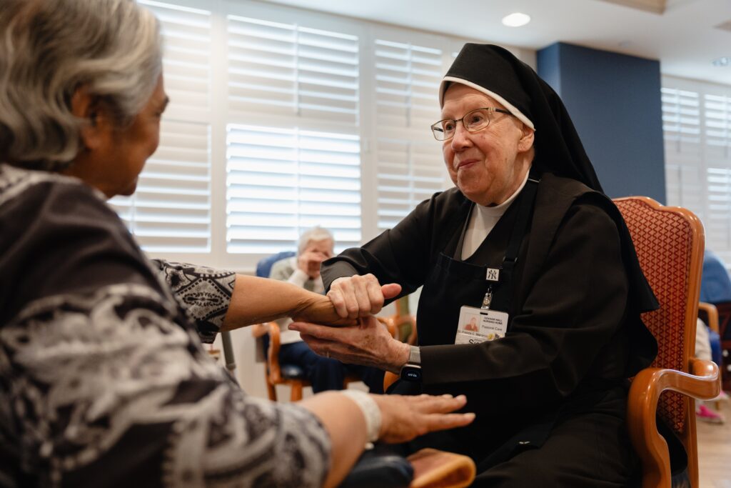 Una hermana carmelita atiende a una residente en Ozanam Hall, ubicado en el vecindario de Bayside, en el distrito de Queens, Nueva York. El 30 de julio de 2026, un juez protegió temporalmente a cuatro órdenes religiosas femeninas y a ministerios católicos de salud de la aplicación de una ley del estado de Nueva York que permite a los médicos ayudar a adultos con enfermedades terminales a morir mediante el suicidio asistido. (Foto de OSV News/cortesía de Becket)
