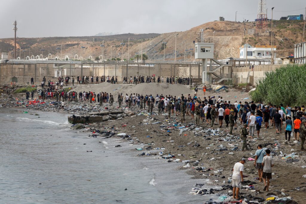 Personas en Ceuta, España, caminan hacia la frontera con Marruecos al abandonar territorio español el 31 de julio de 2026, en medio de cruces masivos de migrantes --a pie y por mar-- desde Marruecos hacia territorio español. La diócesis de Cádiz y Ceuta ofreció recursos de emergencia a las autoridades civiles el 31 de julio, cuando más de 60.000 migrantes cruzaron desde Marruecos al enclave español de Ceuta, lo que saturó la infraestructura local. (Foto OSV News/Jon Nazca, Reuters)