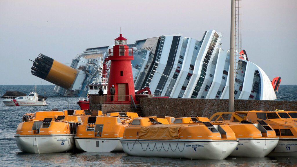 El Costa Concordia, parcialmente volcado, y varios botes salvavidas en la costa. (Rvongher/CC BY-SA 3.0, vía Wikimedia Commons)