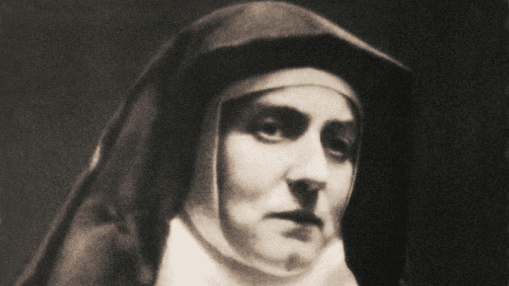 Portrait of a nun in a dark habit with a somber expression, grayscale photo.