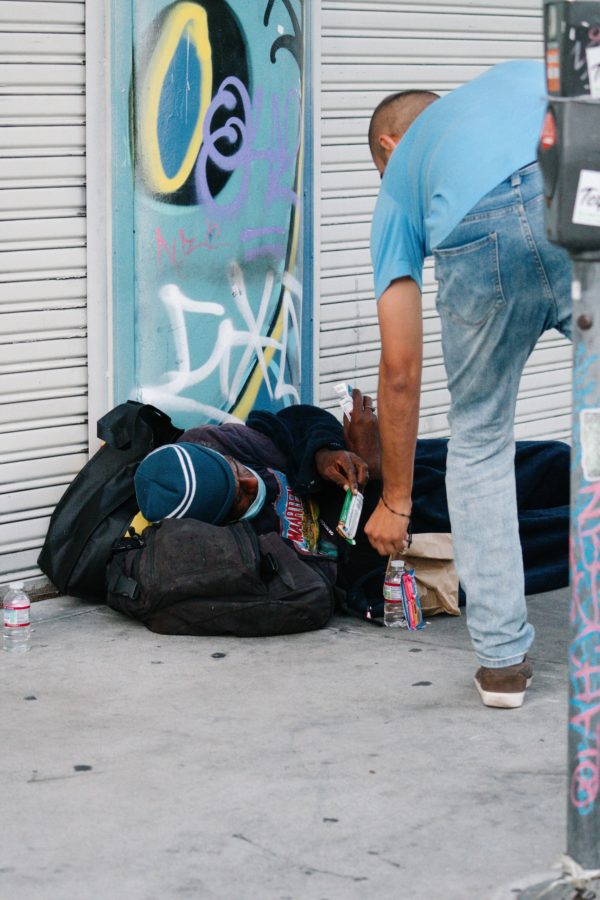 Los participantes se detuvieron para brindar ayuda concreta a las personas sin hogar en las aceras de Skid Row durante la procesión eucarística del 1 de agosto. (Katie Trejo)